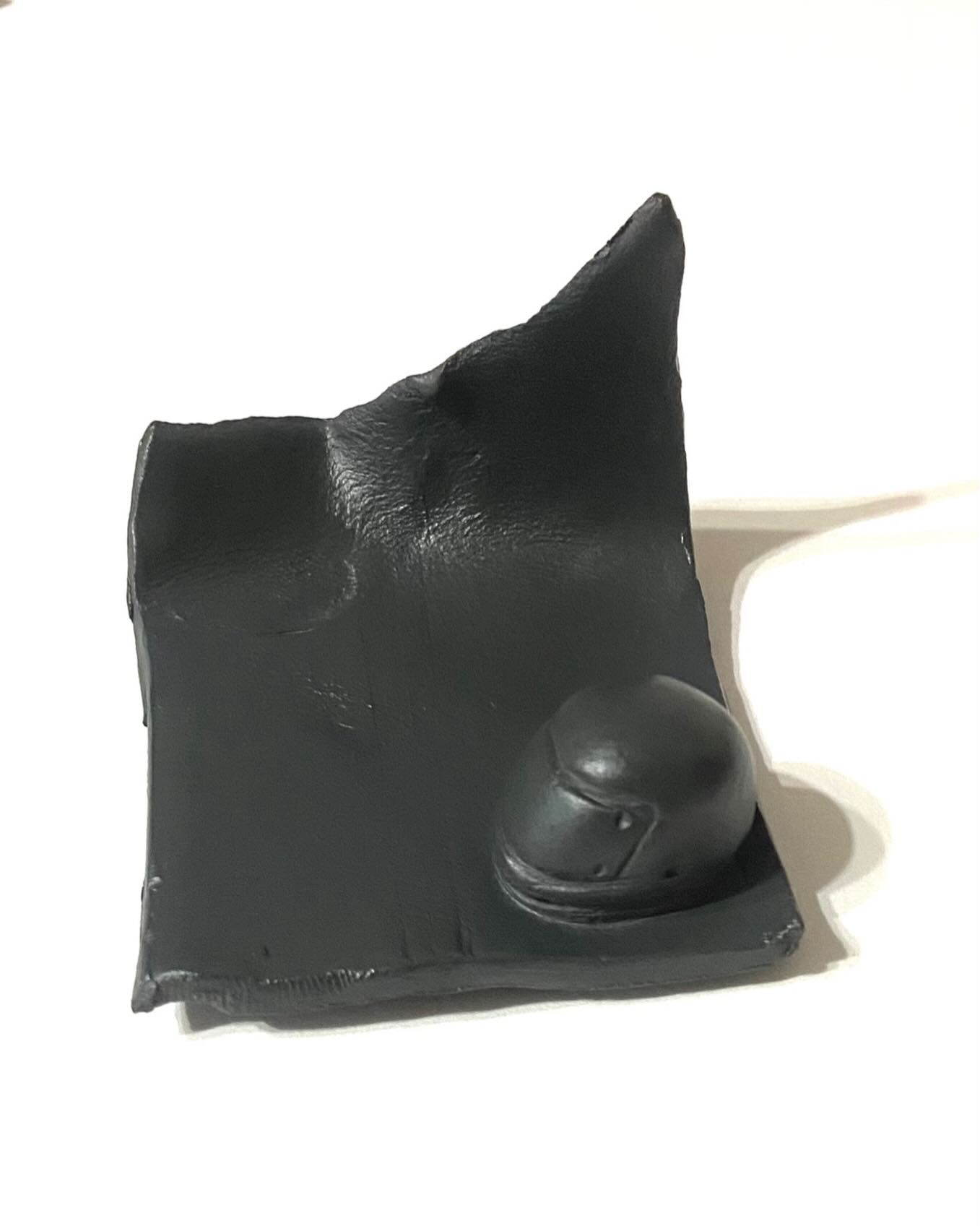 A dark sculptural fragment with an eye